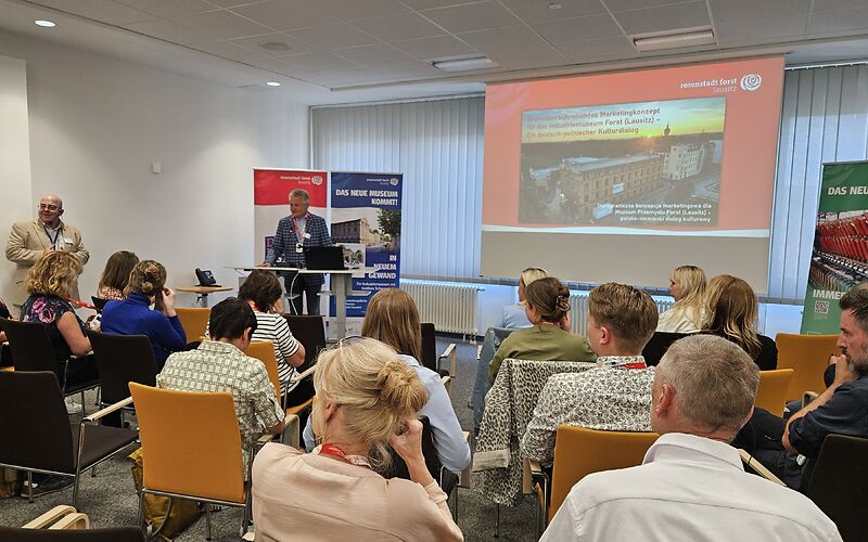Der Präsident der Euroregion Spree-Neisse Czesław Fiedorowicz steht vor dem Pult neben der Präsentation und begrüßt die Gästeür 