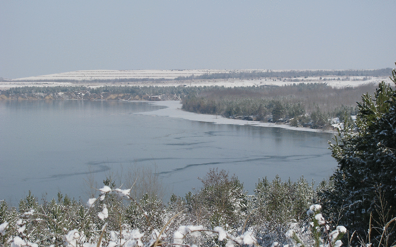 Der Klinger See ist teilweise gefroren, der Landbereich mit Schnee bedeckt