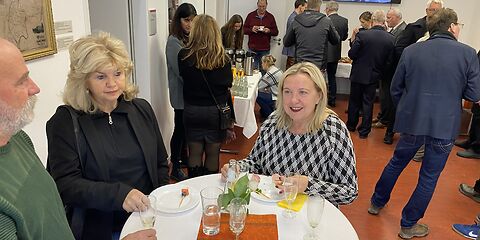Simone Taubenek und Dagmar Klinke an einem runden Tisch im Lesesaal des Archivs. Im Hintergrund stehen weitere Besucher.