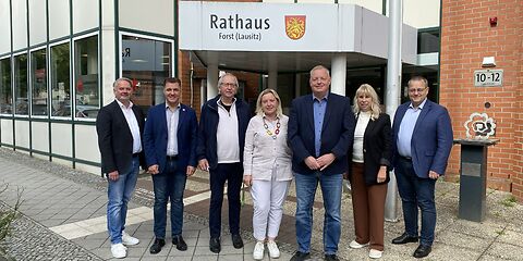 Gruppenfoto vor dem Besuchereingang des Rathauses in der Lindenstraße, im Hintergrund die Grenzrose.