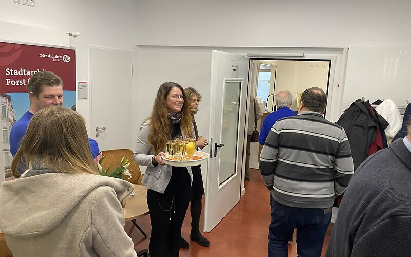 Im Eingangsbereich des Archivs wird Sekt oder Saft zum Anstoßen verteilt.