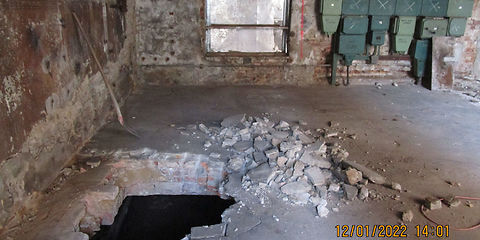 Blick in das ehemalige Heizhaus. In den Fußboden wurde ein Loch zur Be- und Entlüftung während der Dekontamination des Öls im Keller geschlagen.