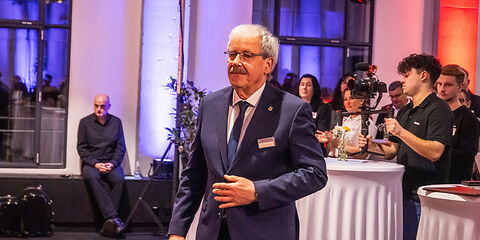 Landrat Harald Altekrüger auf dem Weg zur Bühne. Er trägt einen dunklen Anzug, ein weißes Hemd und eine dunkle Krawatte.