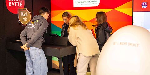 Drei Jugendliche informieren sich am Stand der Brillux Farben GmbH.