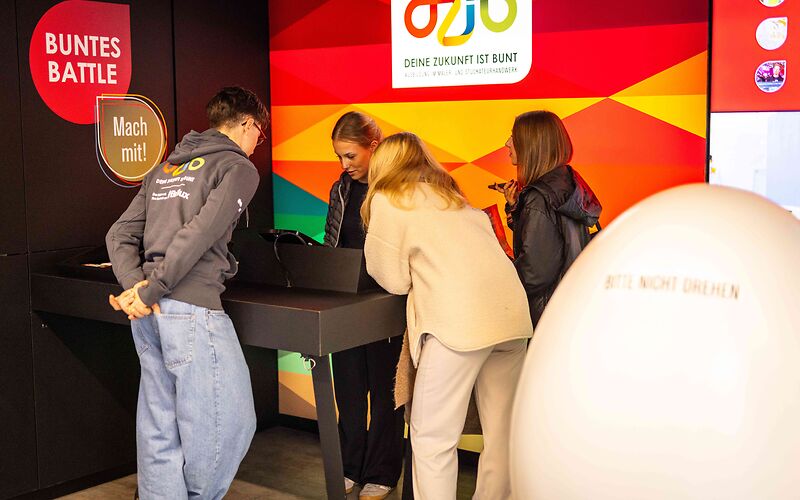 Drei Jugendliche informieren sich am Stand der Brillux Farben GmbH.