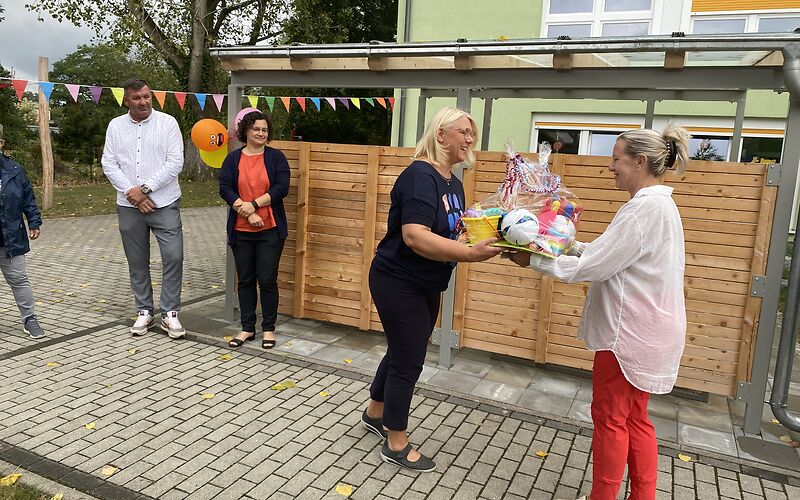 Überreichung eines Präsents auf der Einweihungsfeier vor dem Kita-Gebäude.