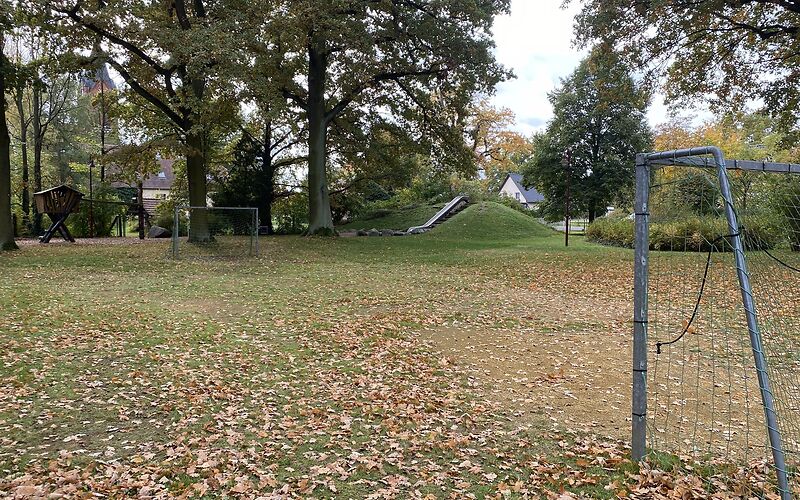 Zwei Fußballtore stehen auf einer Wiese gegenüber, im Hintergrund befindet sich auf an einem Hügel eine Rutsche.