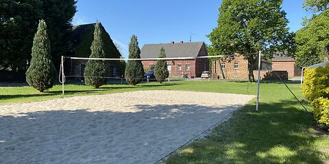 Ein Volleyballfeld mit Sand umgeben von einer Wiese.