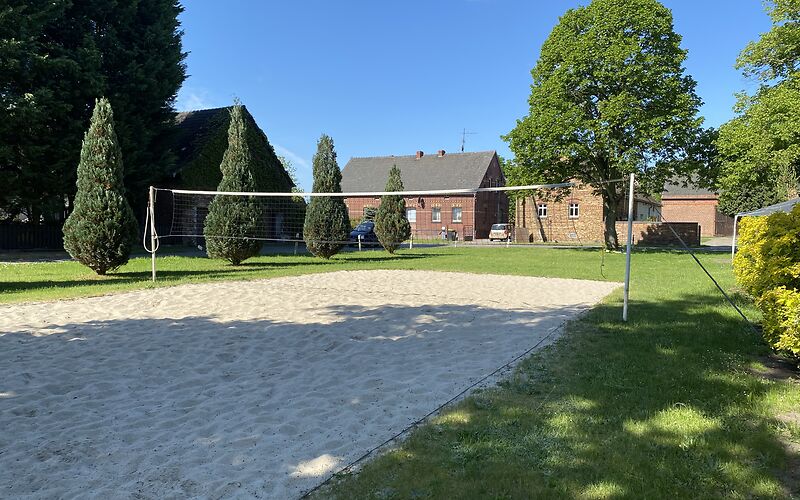Ein Volleyballfeld mit Sand umgeben von einer Wiese.