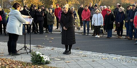 Vor den Stolpersteinen gedenkt die Bürgermeisterin Simone Taubenek den Opfern. Im Hintergrund stehen im Halbkreis die weiteren Teilnehmenden an der Veranstaltung.