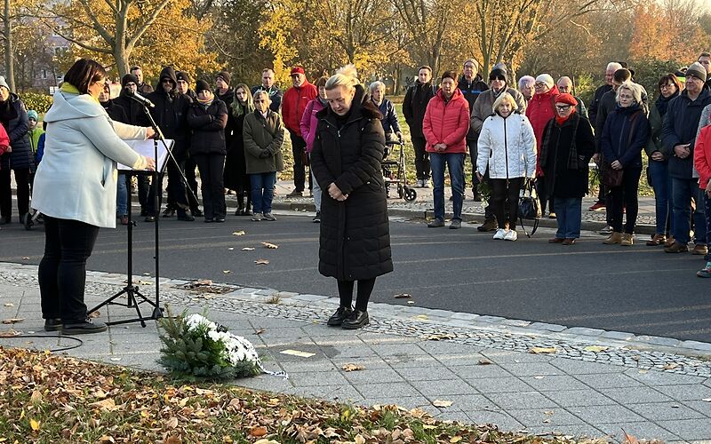 Vor den Stolpersteinen gedenkt die Bürgermeisterin Simone Taubenek Opfern. Im Hintergrund stehen im Halbkreis die weiteren Teilnehmenden an der Veranstaltung.