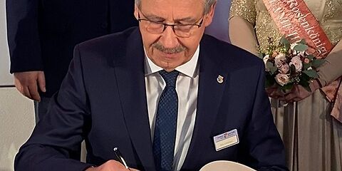 Harald Altekrüger trägt sich an einem Tisch in das Goldene Buch der Stadt Forst (Lausitz) ein. Hinter ihm stehen die Bürgermeisterin, der Vorsitzende der Stadtverordnetenversammlung und die Rosenkönigin.