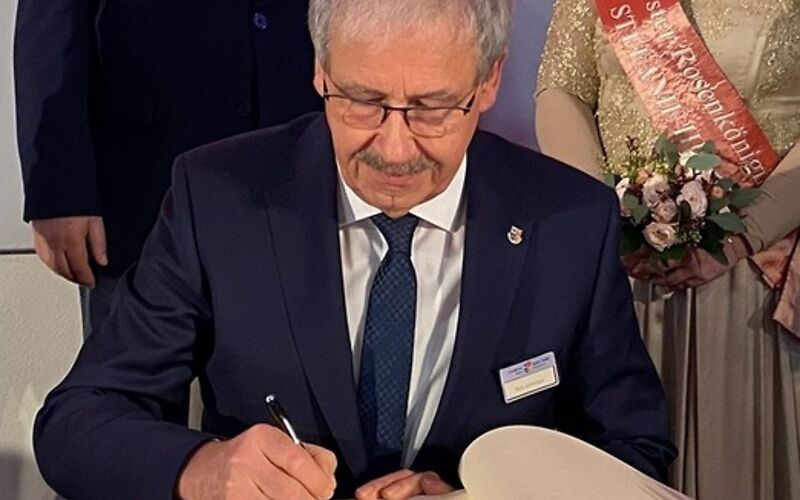 Harald Altekrüger trägt sich an einem Tisch in das Goldene Buch der Stadt Forst (Lausitz) ein. Hinter ihm stehen die Bürgermeisterin, der Vorsitzende der Stadtverordnetenversammlung und die Rosenkönigin.