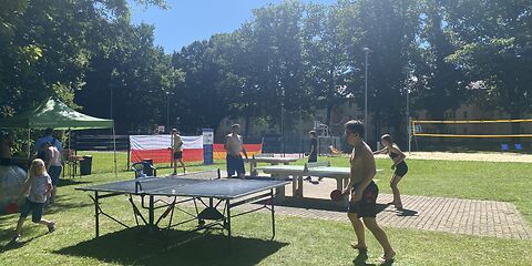 Es stehen 3 Tischtennisplatten nebeneinander, an denen jeweils zwei Personen gegeneinander spielen.