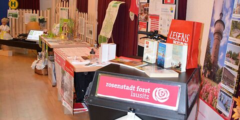 Der Stand der Stadtverwaltung Forst (Lausitz) mit verschiedenen Infomaterialien und einem Aufsteller mit Fotos aus dem Stadtgebiet (Wasserturm, Textilmuseum, Radrennbahn, Rosengarten).