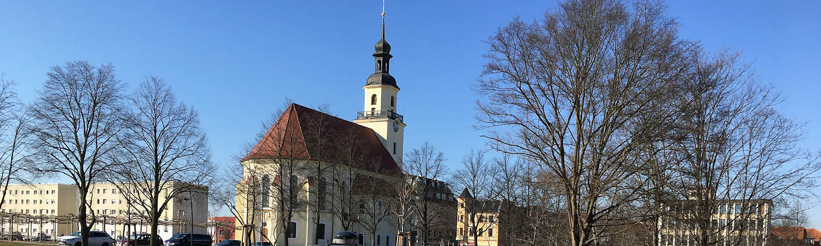 Blick auf das Kirchenschiff der Stadtkirche St. Nikolai umgeben von blätterlosen Bäumen