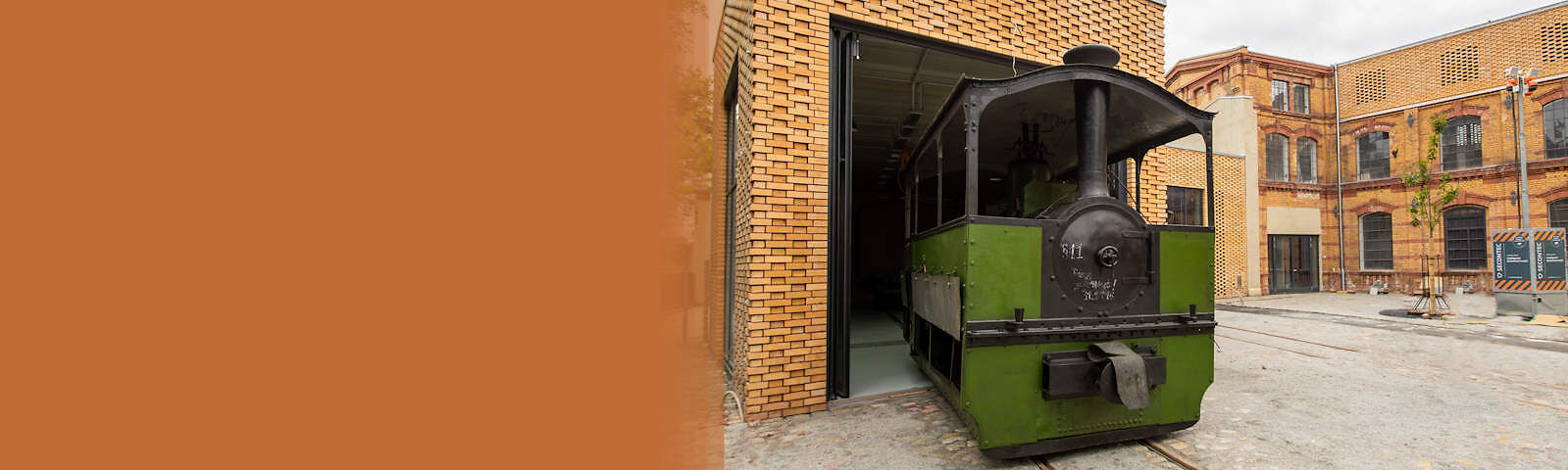 Die "schwarze Jule" - eine grün-schwarze Lokomotive - steht auf Schienen auf dem Innenhof des Museums und fährt in eine kleine Halle. 