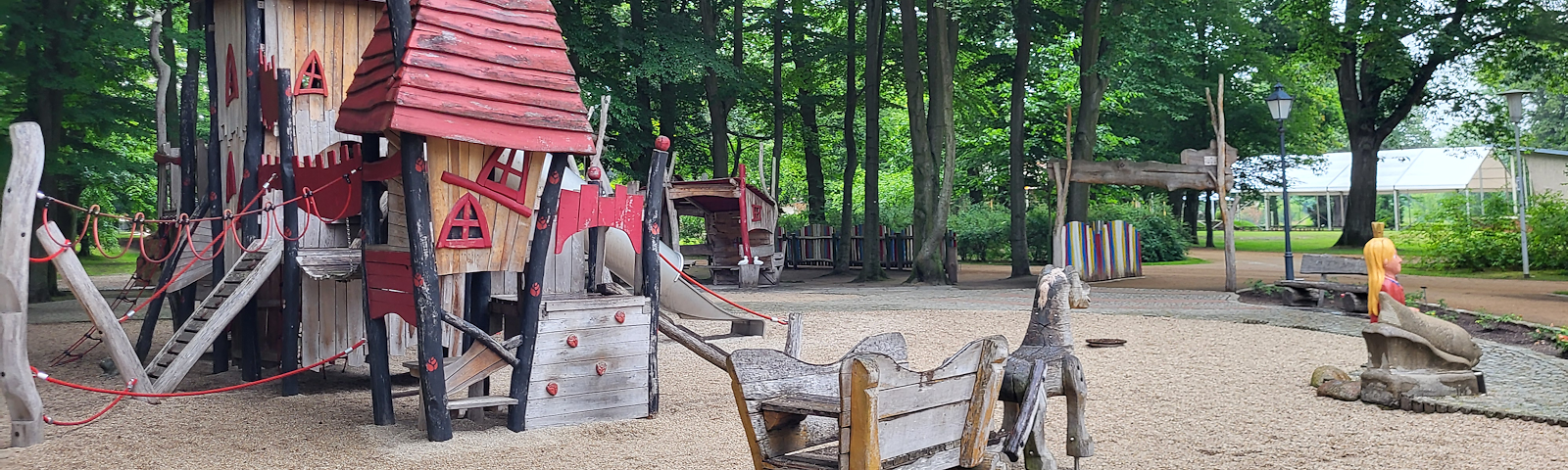 Ein Klettergerüst aus Holz, welches wie ein Märchenschloss aussieht, ein Holzwagen mit hölzernem Tier, welches diese zieht und eine Prinzessin