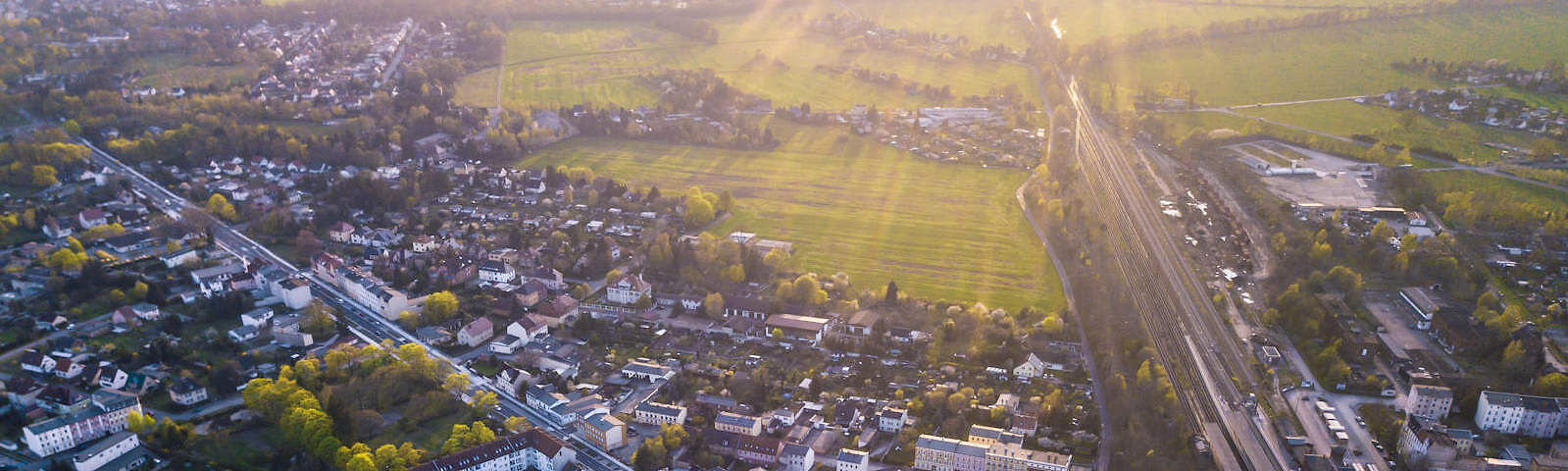 Blick auf die Stadt Forst von oben, Wiesen im hinteren Bereich, auf die Sonnenstrahlen fallen