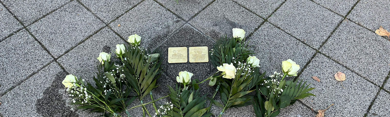 Die Stolpersteine für Ilse und Erna Pick im Gehweg der Mauerstraße, umgeben von weißen Rosen